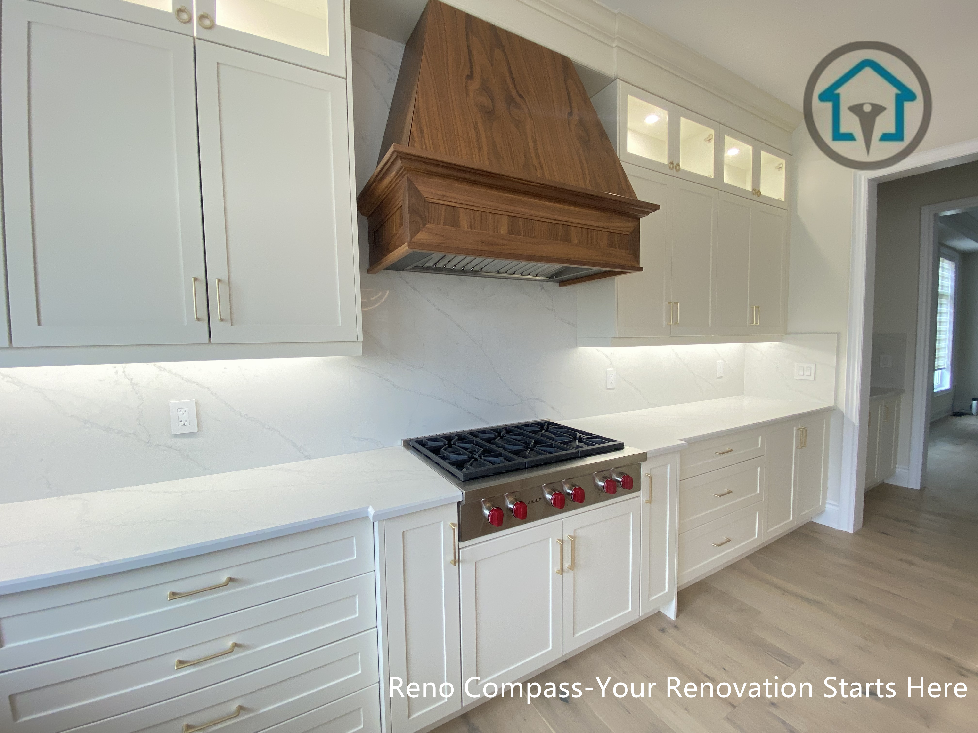 This image highlights a custom cooktop wall in a Richmond Hill interior renovation, featuring a handcrafted wood range hood paired with full-height cabinetry and a clean stone backsplash. Integrated lighting and refined hardware details enhance both functionality and visual balance, while the warm wood element adds contrast to the light-toned kitchen design. Designed and completed by Reno Compass, this kitchen renovation reflects a thoughtful blend of craftsmanship and modern practicality for homes in Richmond Hill.