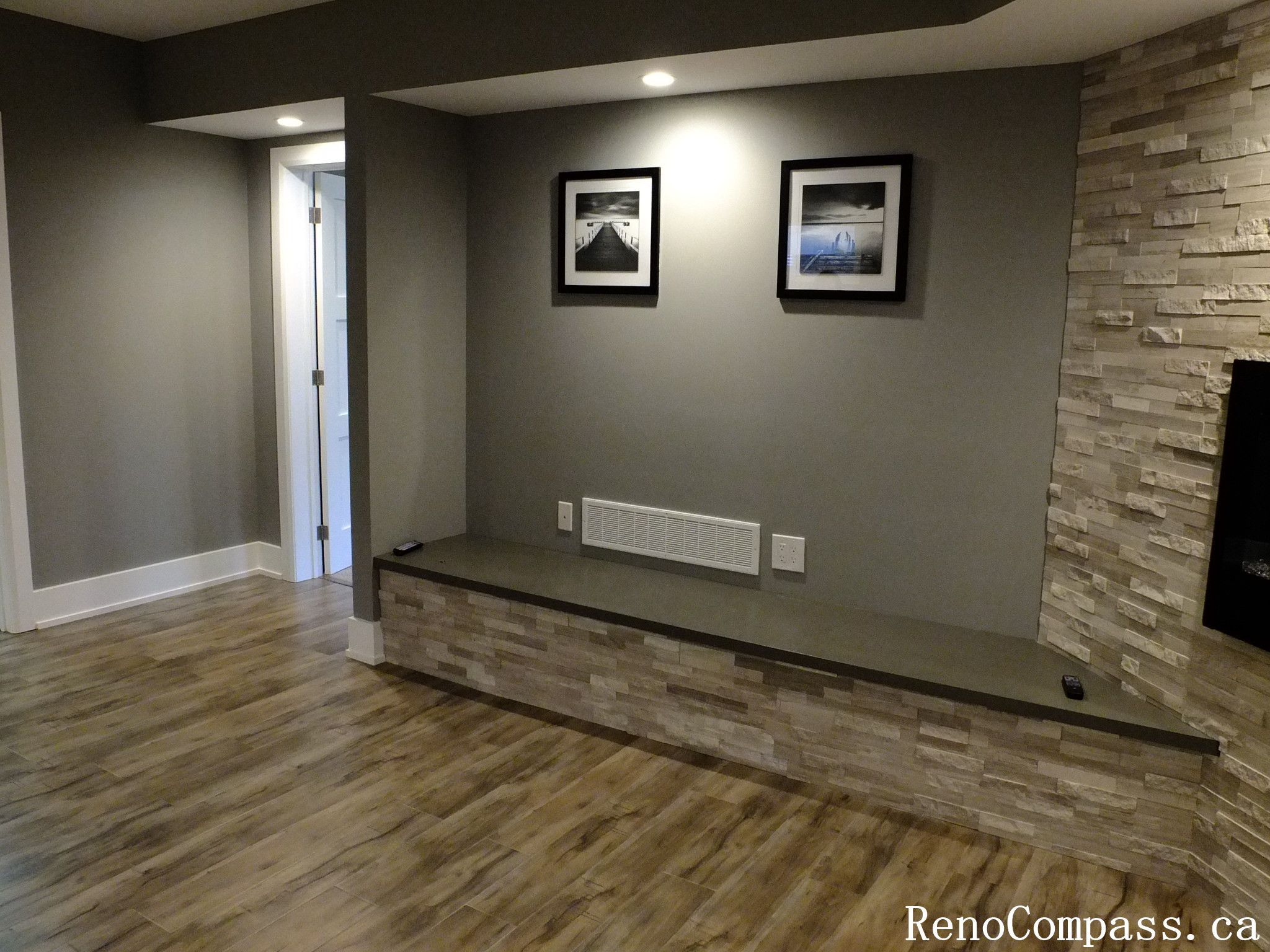 Modern finished basement in Waterloo featuring a stunning stone feature wall, built‑in electric fireplace, recessed lighting, and a custom bench with matching stone accents. A stylish focal point in the renovated lower level.