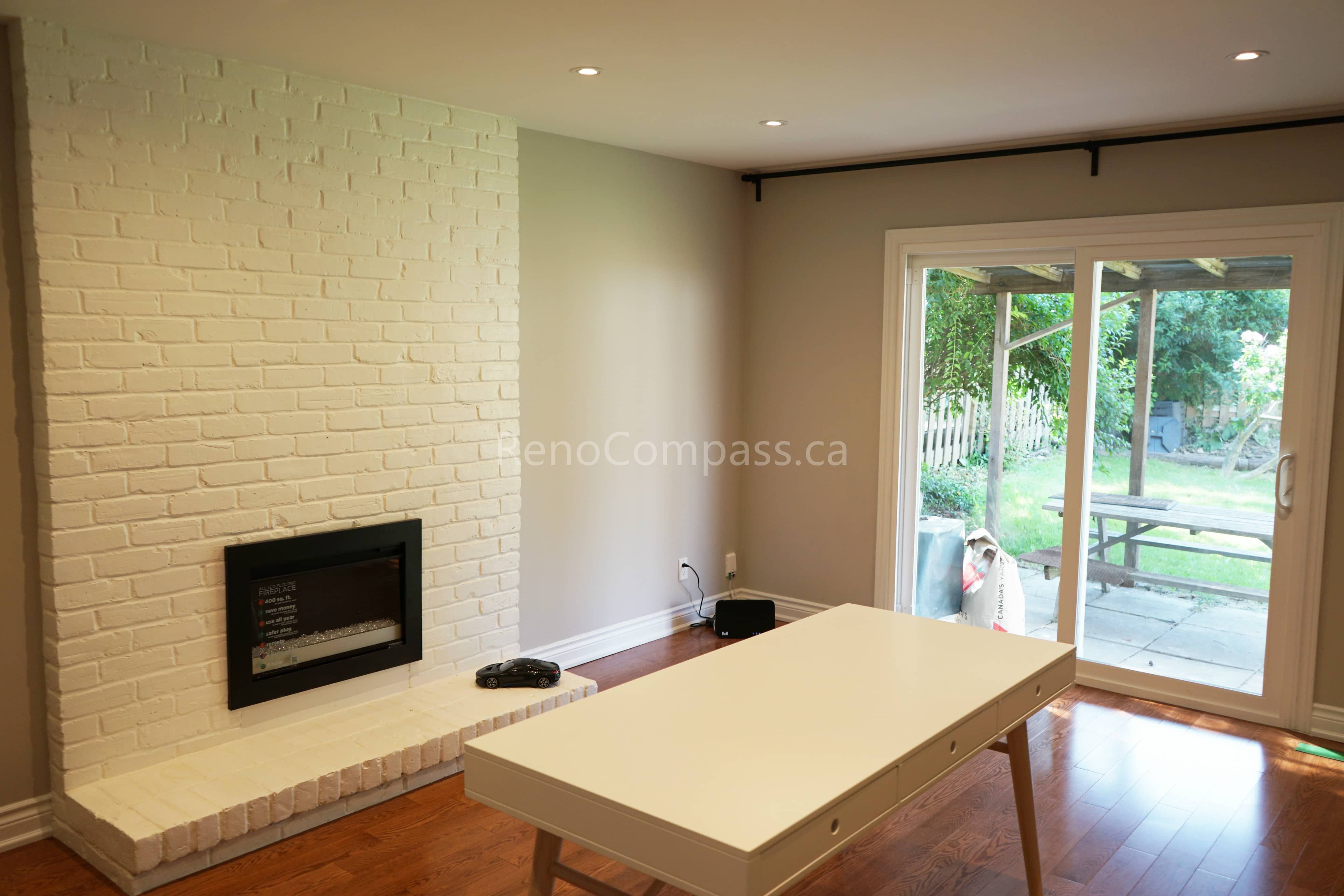 his North York interior renovation showcases an open living space featuring a white brick fireplace, hardwood flooring, and large patio doors that enhance natural light and indoor-outdoor flow. The clean layout and recessed lighting create a bright and functional environment ideal for family living. Completed by a professional Toronto renovation company, this project highlights thoughtful space planning and quality interior renovation craftsmanship for Toronto homes.
