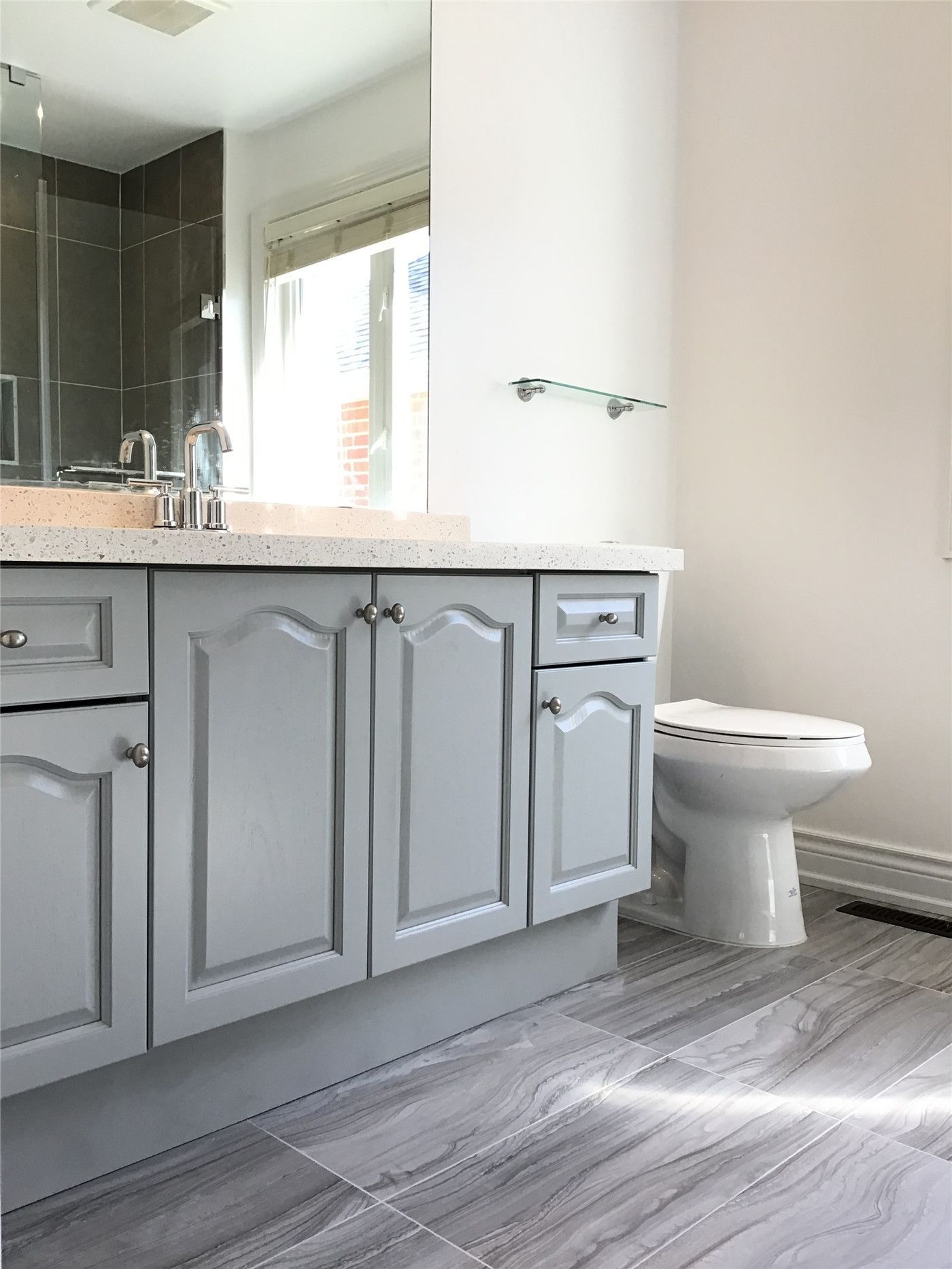 This Woodbridge interior renovation highlights a functional bathroom vanity upgrade featuring grey cabinetry, a durable quartz countertop, and integrated sink. Paired with modern floor tiles and a clean layout, the design offers a practical, low-maintenance solution for everyday use.