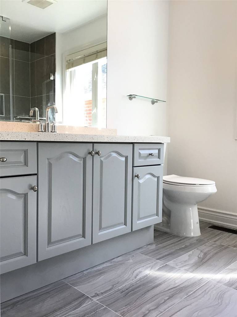 This Woodbridge interior renovation highlights a functional bathroom vanity upgrade featuring grey cabinetry, a durable quartz countertop, and integrated sink. Paired with modern floor tiles and a clean layout, the design offers a practical, low-maintenance solution for everyday use.