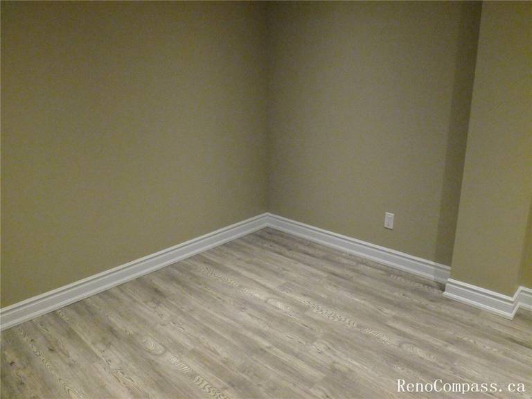 A complete look at a finished basement project in Ajax, Ontario. This bright, open-concept recreation room features energy-efficient pot lights, updated windows for natural light, and a modern neutral color palette. Professional basement finishing by Reno Compass.
