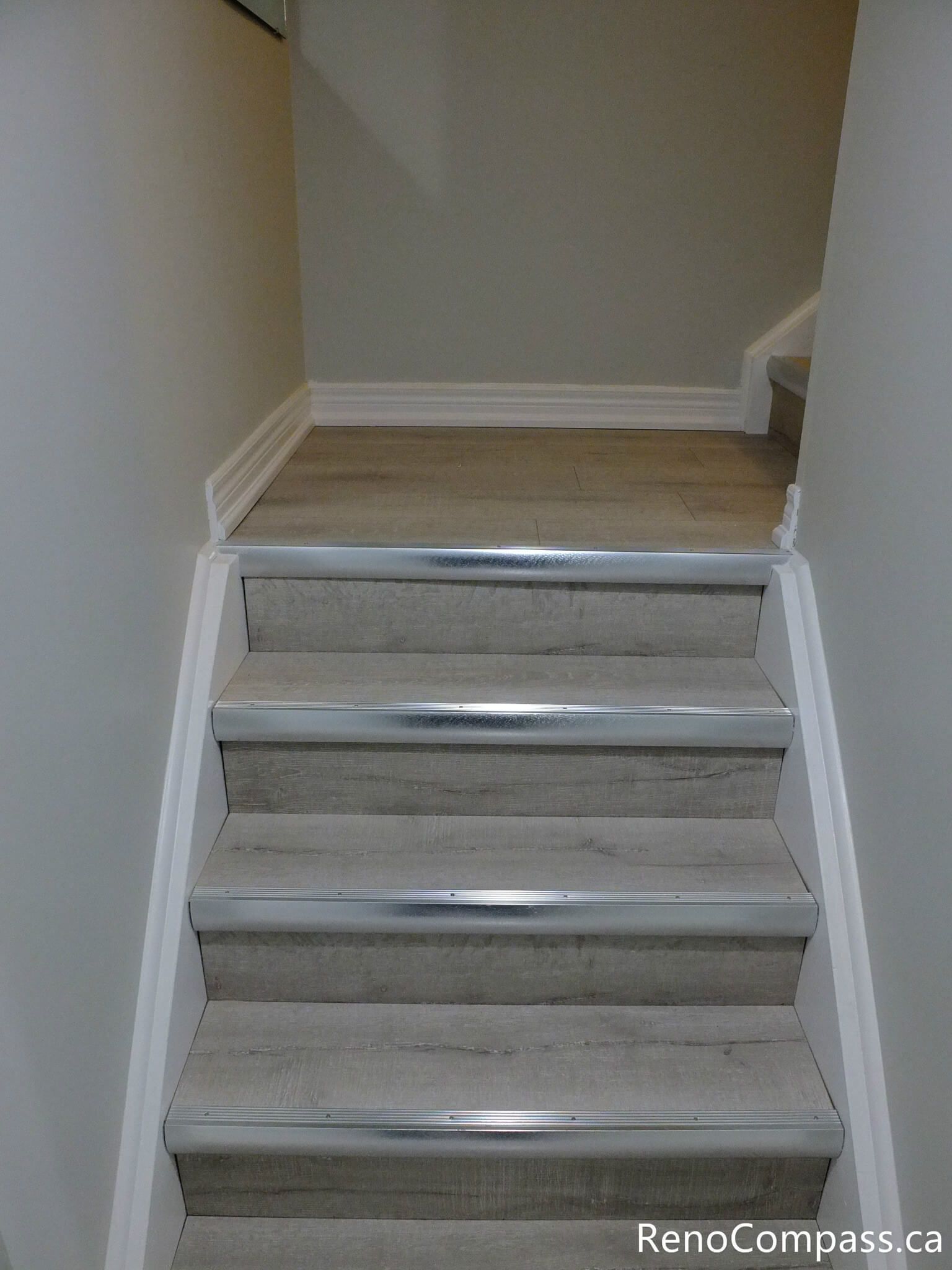 This Markham basement staircase renovation features durable wood-look vinyl steps paired with clean white trim for a modern and cohesive transition between levels. The updated stair design enhances safety, durability, and visual consistency with the rest of the finished basement space. Completed by a professional Toronto Renovation Company, Reno Compass Inc.