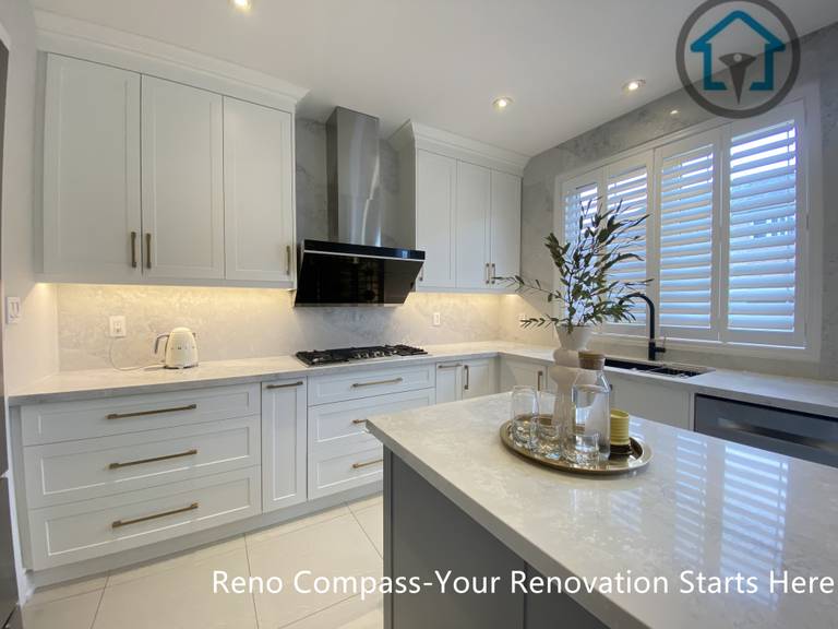 This image showcases the relationship between the central kitchen island and the main working zone in this Markham kitchen renovation. The layout combines custom white cabinetry, a gas cooktop wall, and a spacious island designed for prep, gathering, and daily use. Natural light from the window and integrated lighting enhance the sense of openness and balance. Designed and built by Reno Compass, this kitchen reflects a practical yet refined approach to modern kitchen renovation in Markham.