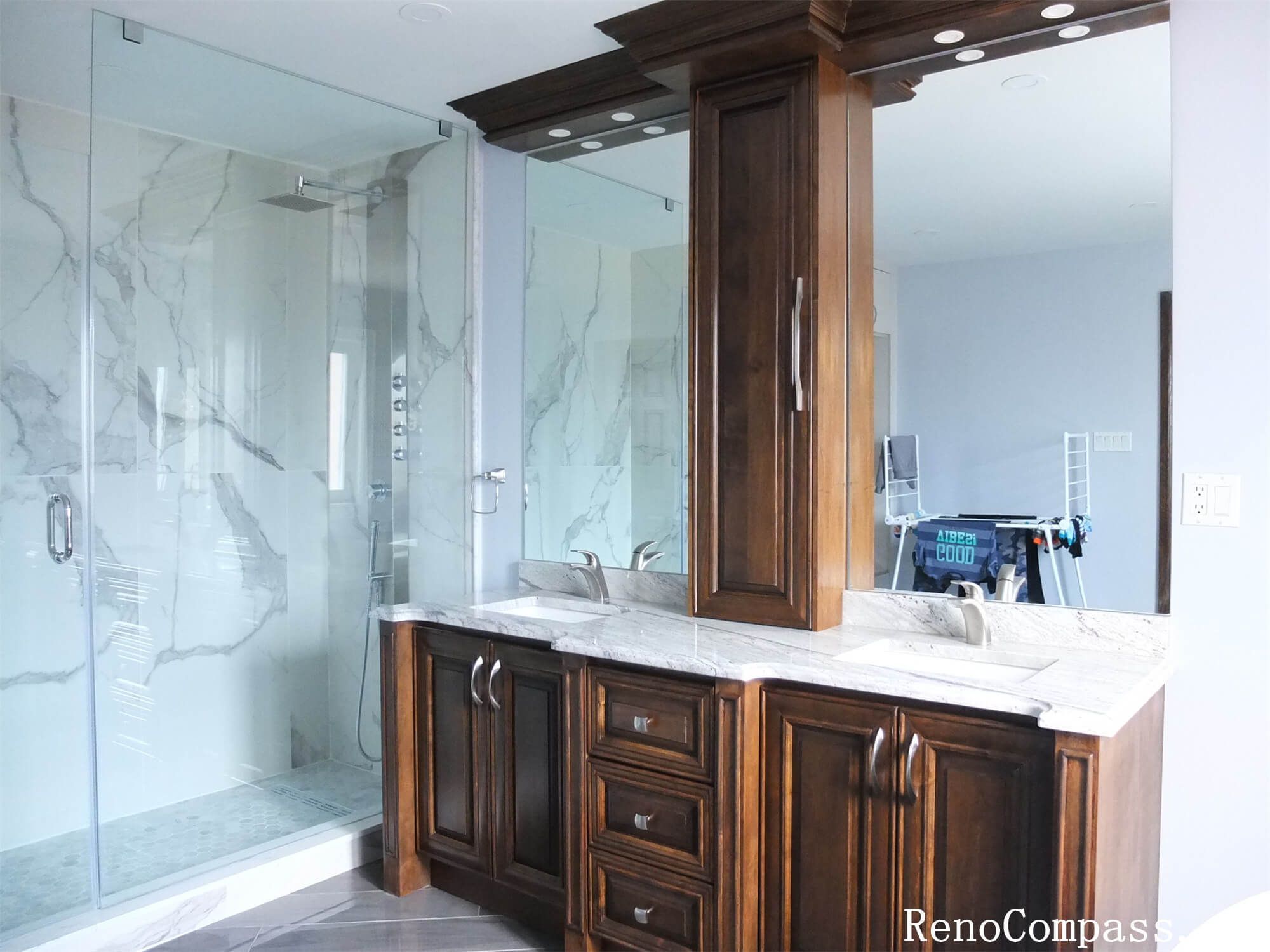 This Richmond Hill interior renovation showcases a modern luxury bathroom featuring a frameless glass walk-in shower, marble-style wall tiles, and custom solid wood vanity cabinetry with quartz countertops. The spacious layout improves functionality while maintaining an elegant and timeless design. Large mirrors, upgraded lighting, and durable floor tiles enhance both comfort and usability for daily living. Completed by a professional Toronto renovation company, this bathroom renovation combines high-end finishes with practical design to increase home value and long-term performance.