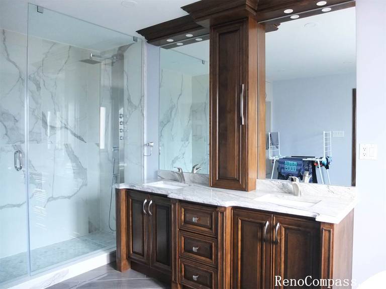 This Richmond Hill interior renovation showcases a modern luxury bathroom featuring a frameless glass walk-in shower, marble-style wall tiles, and custom solid wood vanity cabinetry with quartz countertops. The spacious layout improves functionality while maintaining an elegant and timeless design. Large mirrors, upgraded lighting, and durable floor tiles enhance both comfort and usability for daily living. Completed by a professional Toronto renovation company, this bathroom renovation combines high-end finishes with practical design to increase home value and long-term performance.