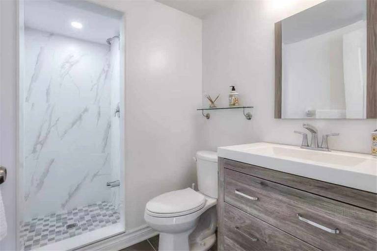 This Thornhill bathroom renovation features a modern walk-in shower with marble-style wall tiles and mosaic shower floor, paired with a contemporary vanity and quartz countertop. The clean layout, updated fixtures, and neutral color palette create a bright and functional bathroom space. Completed by a professional Toronto renovation team, this upgrade delivers a stylish and practical bathroom design suited for modern family living.