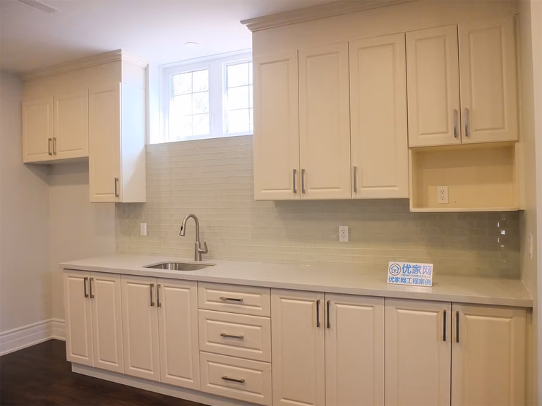 This Richmond Hill basement renovation includes a functional kitchen area featuring custom cabinetry, a built-in sink, and a clean tile backsplash. The light-colored cabinets combined with modern hardware create a bright and practical space, ideal for a basement bar, secondary kitchen, or rental suite setup.