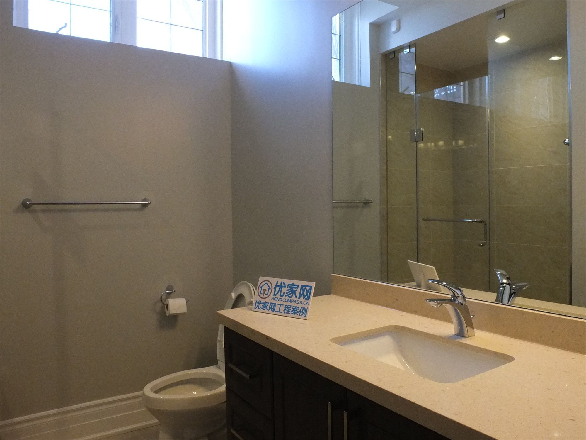 This Richmond Hill basement renovation features a modern bathroom vanity with a quartz countertop, large mirror, and stylish overhead lighting. The clean design and warm lighting enhance both functionality and aesthetics, creating a bright and polished bathroom space.