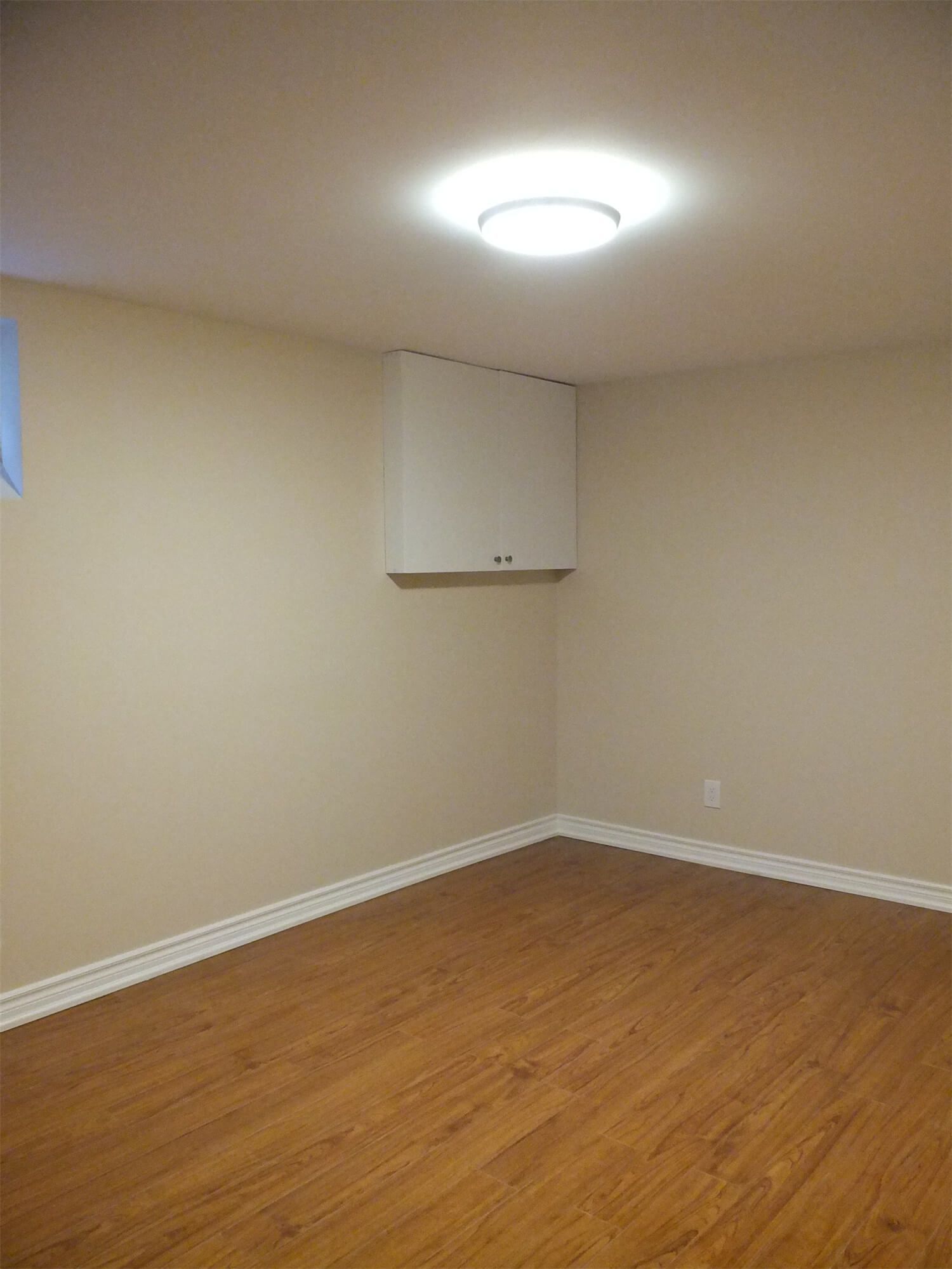 This Markham basement renovation project features newly finished walls, fresh interior painting, and durable laminate flooring installation. The clean wall finish, neutral paint tones, and wood-style flooring create a bright, comfortable living space suitable for a family recreation room or additional living area. Careful detailing around the baseboards and wall edges ensures a smooth and polished appearance throughout the basement interior.