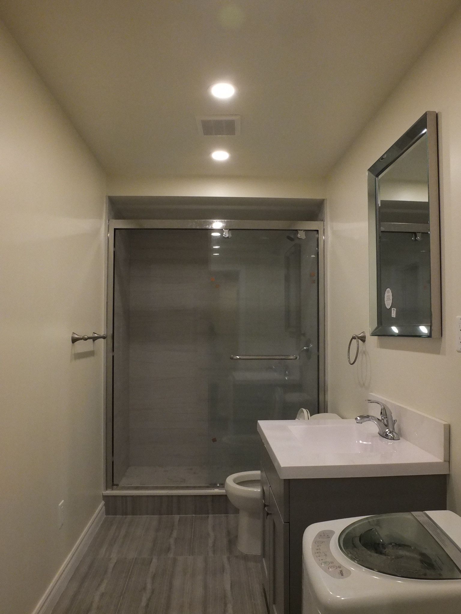 This Vaughan basement bathroom renovation, completed by a professional Toronto Renovation Company, features a sleek glass-enclosed shower, modern vanity, and durable waterproof flooring designed for everyday comfort. Recessed ceiling lighting enhances brightness while neutral finishes create a clean, contemporary look. The compact yet functional layout maximizes space efficiency, making the bathroom ideal for guest use or family convenience. This finished basement bathroom adds both practicality and long-term value to the home while maintaining a modern and low-maintenance design.