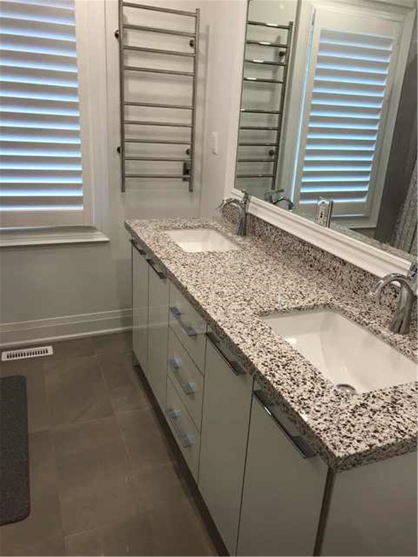 This North York bathroom renovation features a double vanity with granite countertops, dual undermount sinks, and ample built-in storage. The layout improves daily usability for shared bathrooms, while neutral finishes and clean lines create a practical and timeless bathroom design.