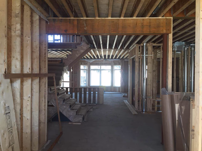Structural framing stage of a Toronto design build custom build project, showing exposed wooden beams, framing structures, and staircase installation during early construction. This phase is part of a whole house renovation Toronto and custom home build, where precise structural work ensures a strong foundation for the interior layout, staircases, and open living spaces in modern luxury homes across Toronto.