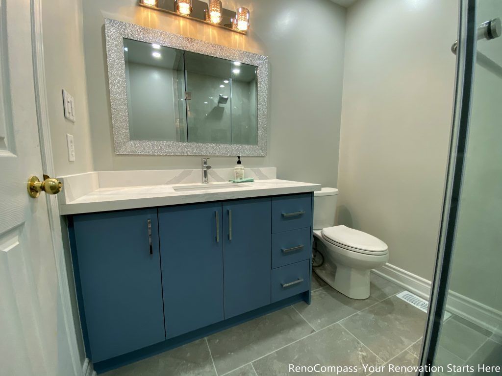 This Mississauga bathroom renovation showcases a custom vanity with blue cabinetry, a clean white countertop, and integrated storage drawers. A framed mirror and warm lighting add balance to the space, while the layout focuses on everyday functionality and efficient use of floor area. Neutral finishes help keep the bathroom feeling bright and well-organized.
City: Mississauga · Toronto contractor: Reno Compass