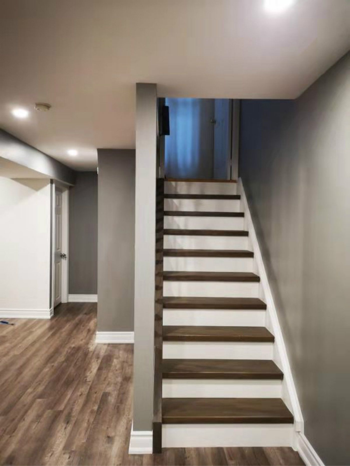 This finished Mississauga basement features a modern staircase with wood treads, white risers, and a clean open design. Paired with upgraded flooring and recessed lighting, the space reflects high-quality craftsmanship by a professional Toronto renovation company, enhancing both safety and contemporary style.