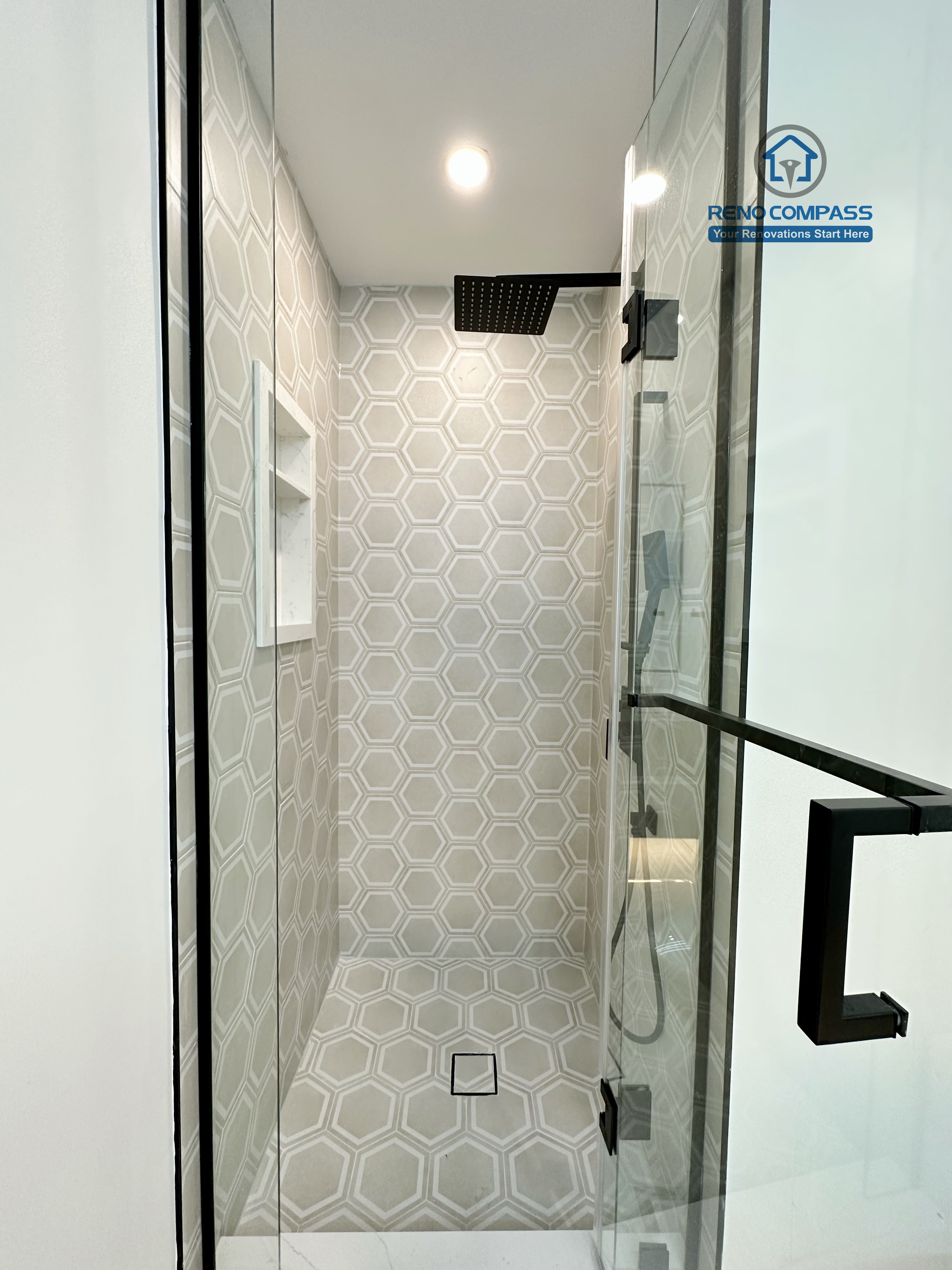 Modern bathroom renovation in Richmond Hill showcasing a walk-in glass shower with hexagon tile walls and flooring, built-in shower niche, and matte black fixtures for a clean, contemporary, and highly functional design.
