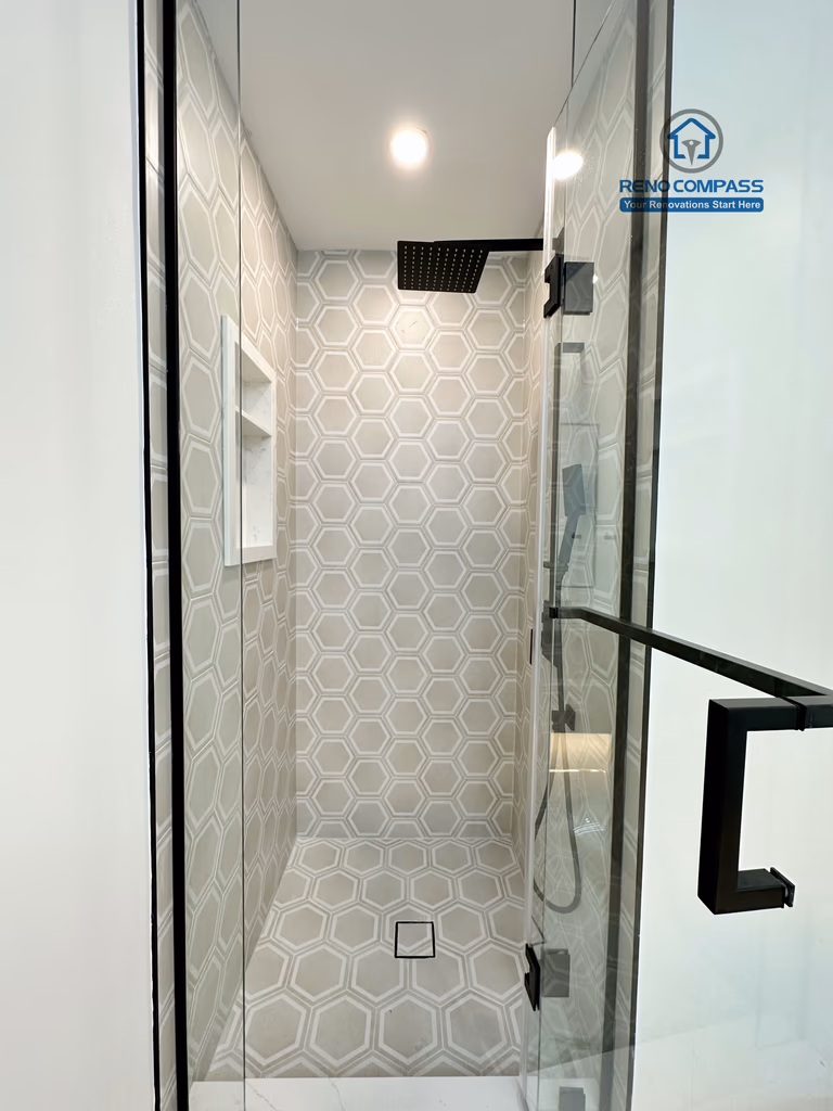 Modern bathroom renovation in Richmond Hill showcasing a walk-in glass shower with hexagon tile walls and flooring, built-in shower niche, and matte black fixtures for a clean, contemporary, and highly functional design.