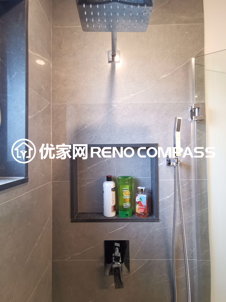 This image highlights a detailed view of a walk-in shower completed as part of a North York interior renovation project. The shower features a ceiling-mounted rain shower head, a handheld shower system, and a built-in wall niche for convenient storage. Large-format wall tiles create a clean and cohesive look, while the recessed niche adds both functionality and visual depth. The modern fixture layout and precise tile installation demonstrate quality craftsmanship and thoughtful bathroom design tailored for contemporary Toronto homes.