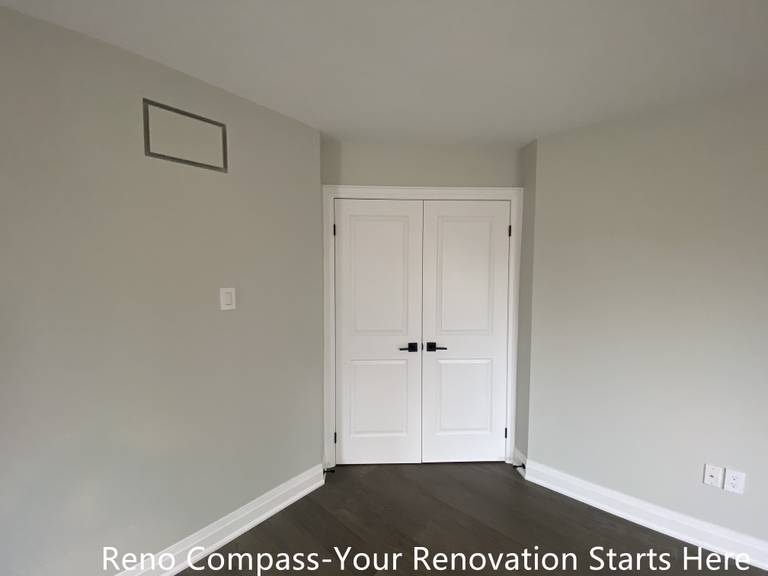 Finished interior room featured in an Oakville interior renovation, highlighting clean wall finishes, modern dark-tone flooring, and classic white double doors. This space reflects precise workmanship, neutral color selection, and functional design completed by a professional Toronto renovation company.