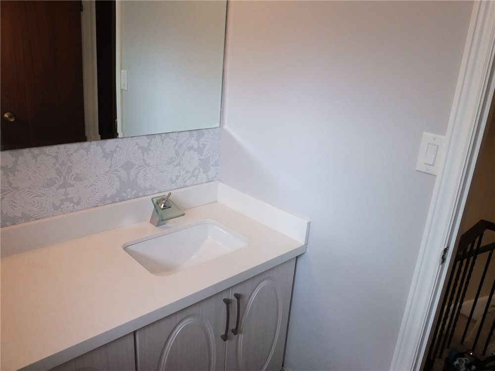 This North York bathroom renovation features a sleek vanity with a quartz countertop, integrated sink, and contemporary faucet design. The bright finishes, decorative backsplash, and large mirror enhance both functionality and visual space. Completed by a professional Toronto renovation company, the upgrade delivers a clean, modern bathroom style with durable materials and practical storage.