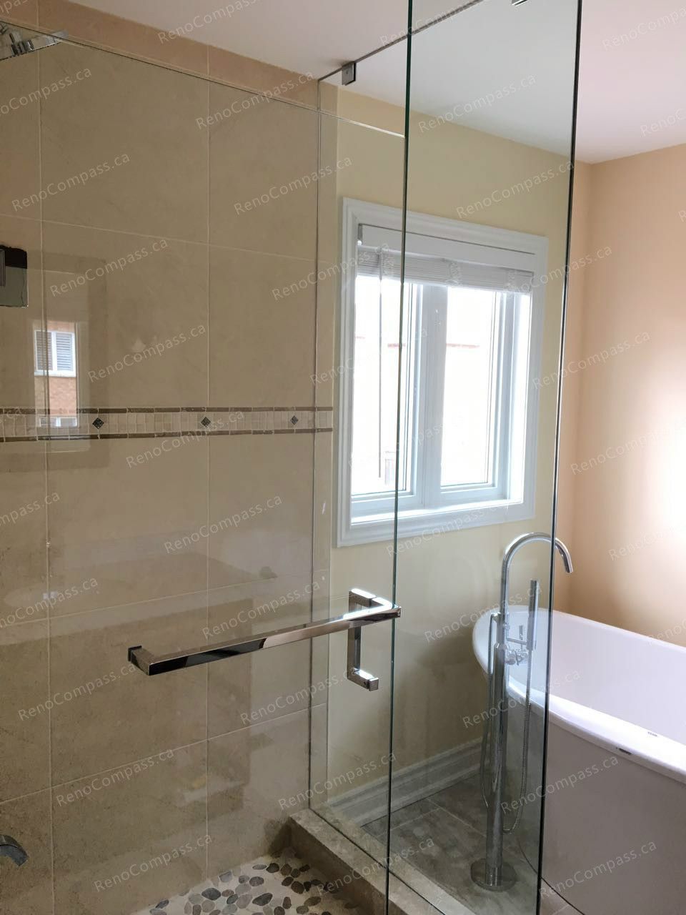 This Markham interior renovation showcases a modern bathroom featuring a frameless glass shower, freestanding bathtub, and large-format wall tiles. Natural light from the window enhances the warm neutral tones and creates a bright, spa-like atmosphere. Completed by a trusted Toronto renovation company, the renovation combines elegant design, improved functionality, and high-quality finishes for a comfortable everyday living experience.