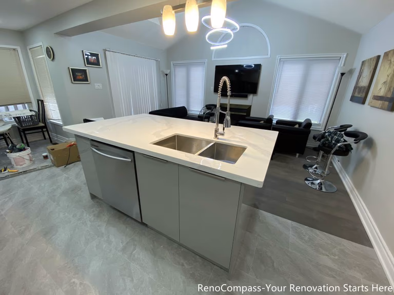 This Mississauga interior renovation features a modern open-concept kitchen with a spacious quartz island, double undermount sink, and sleek contemporary cabinetry. The upgraded layout seamlessly connects the kitchen to the living and dining areas, creating a bright and functional space ideal for everyday living and entertaining. Pendant lighting, durable flooring, and stainless steel appliances enhance both style and practicality. Completed by a trusted Toronto renovation company, this kitchen renovation improves workflow, storage, and overall home value while delivering a clean modern design.