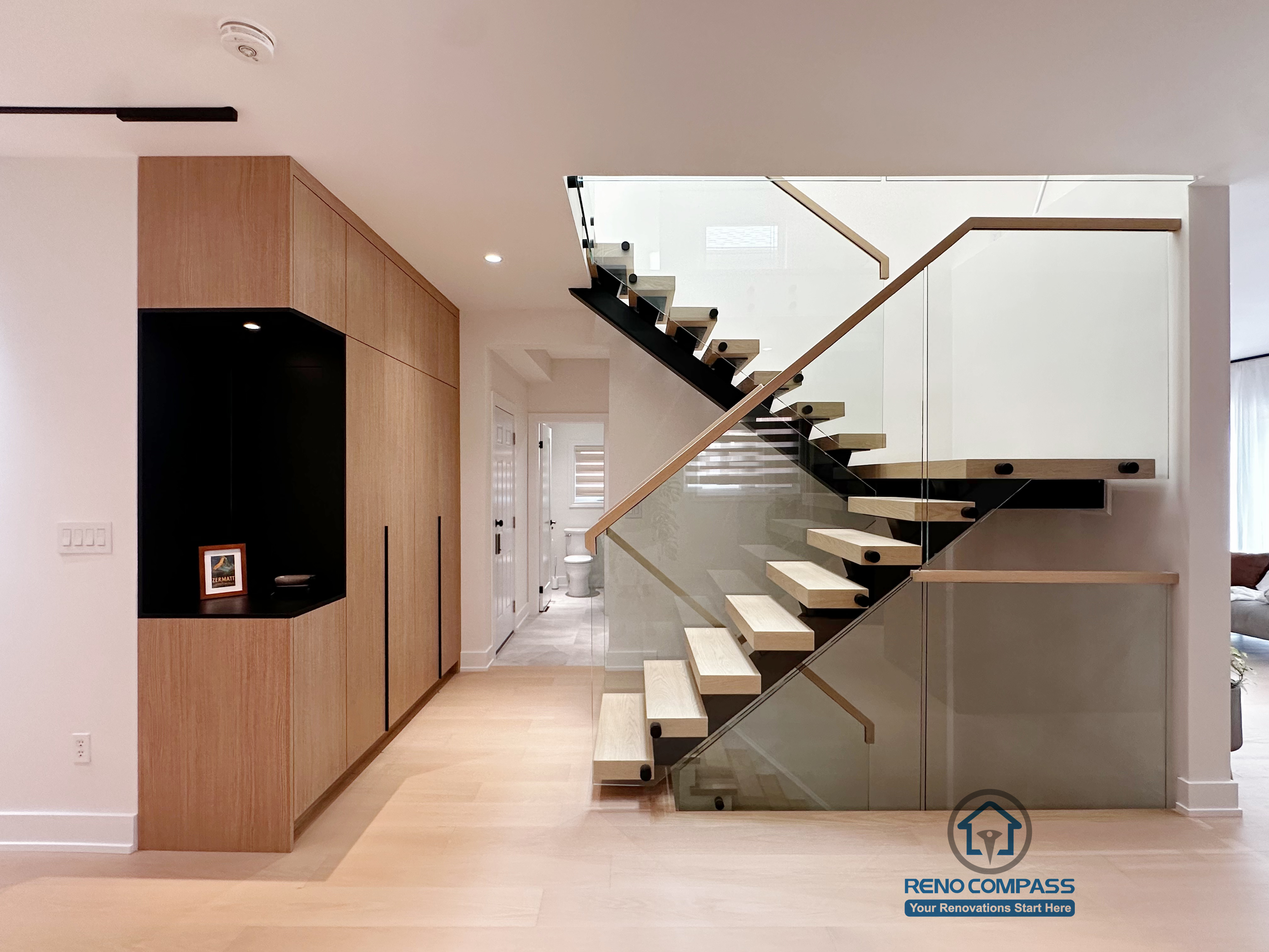 Floating steel staircase integrated with custom wood storage cabinetry in a Markham home renovation, combining open design with practical entryway functionality.