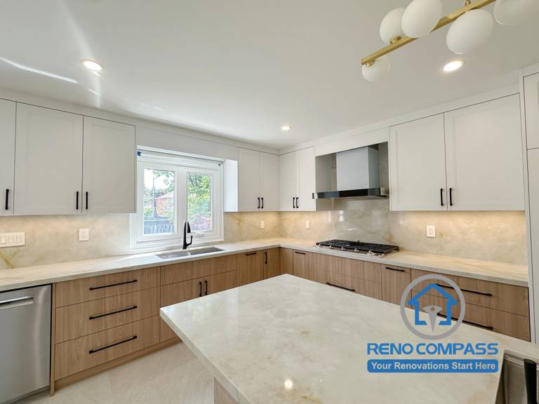 A modern kitchen featuring a large quartz island, custom two-tone cabinetry, quartz countertops, under-cabinet lighting, and premium stainless steel appliances. Completed as part of a luxury whole home renovation in Markham, Ontario, this open-concept kitchen combines timeless design, practical storage, and expert craftsmanship by Reno Compass.