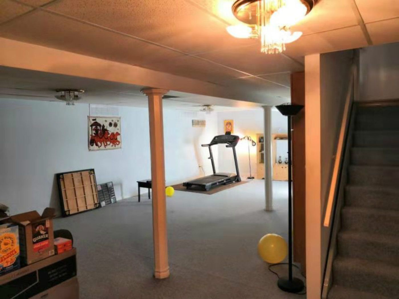 This Mississauga basement features a large open area with structural columns, carpet flooring, and a staircase access point. The space includes basic lighting and a home gym setup, highlighting its potential for a full renovation. A professional Toronto renovation company can transform this basement into a modern, multi-functional living space with improved layout, lighting, and finishes.