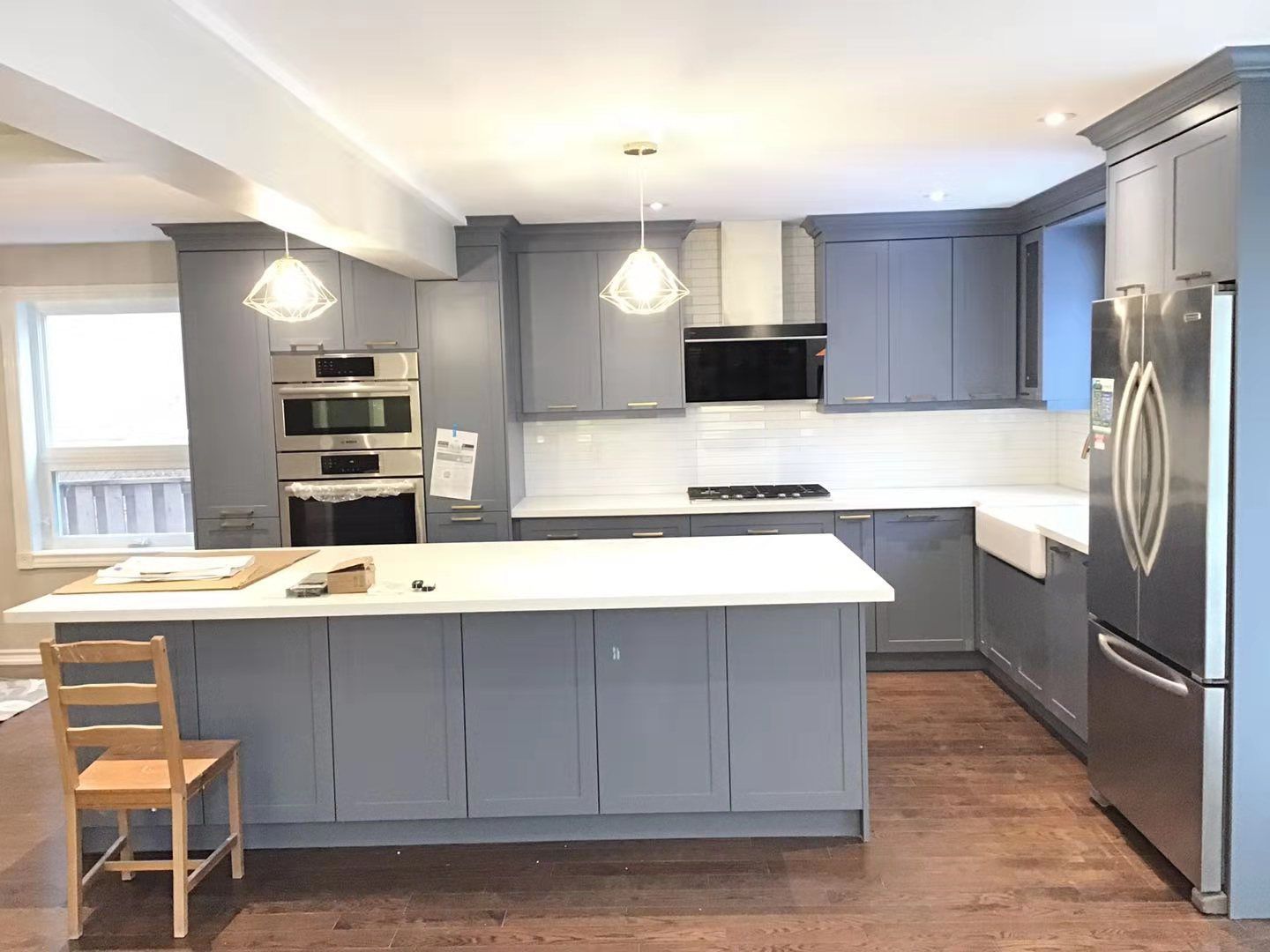 This Richmond Hill interior renovation features a modern grey kitchen design with custom cabinetry, quartz countertops, built-in oven and microwave, and a spacious central island. The open-concept layout enhances functionality and natural lighting, creating a clean and elegant cooking space. Completed by professional Toronto renovation company Reno Compass Inc., this project highlights quality craftsmanship, smart storage solutions, and contemporary finishes ideal for modern family living.