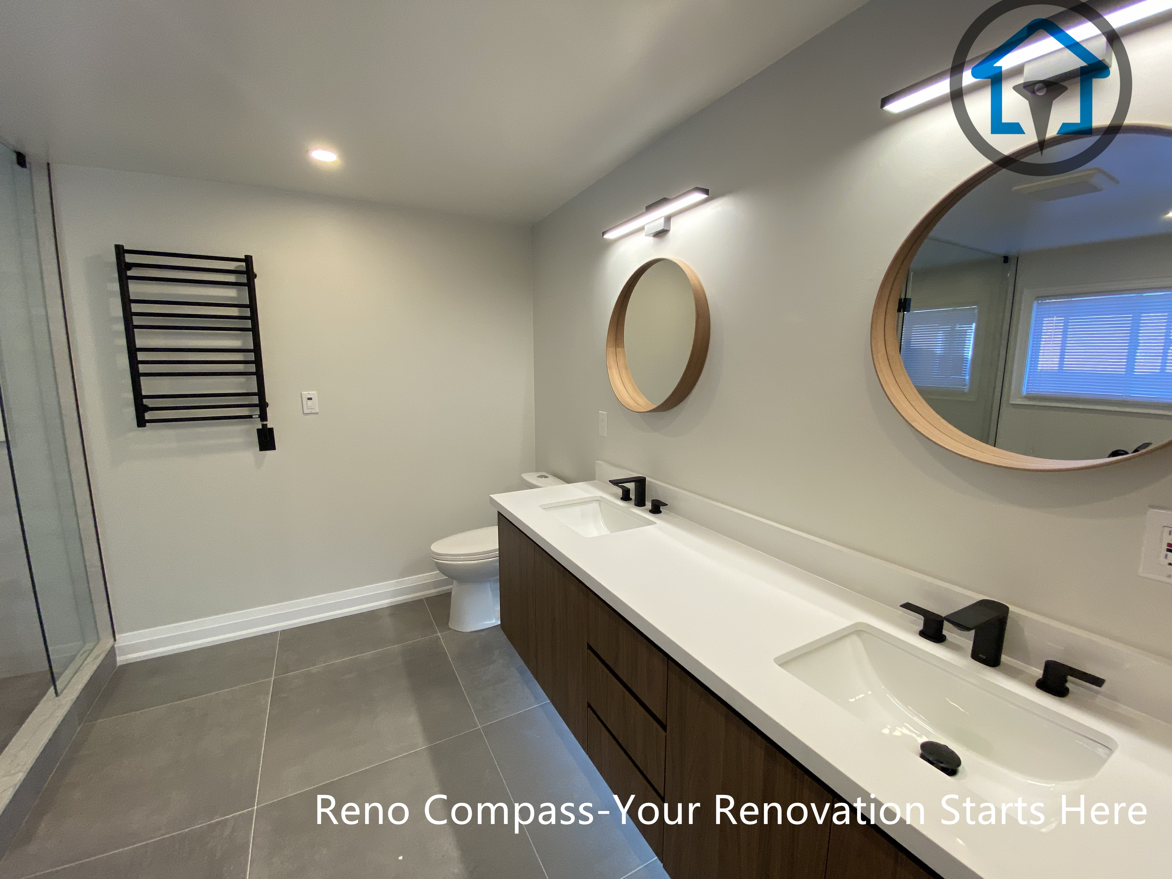 Contemporary bathroom renovation in Markham showcasing a custom double sink vanity, integrated LED mirror lighting, matte black faucets, and large-format floor tiles. The design balances clean lines, warm wood tones, and practical storage, completed by a trusted Toronto renovation company.