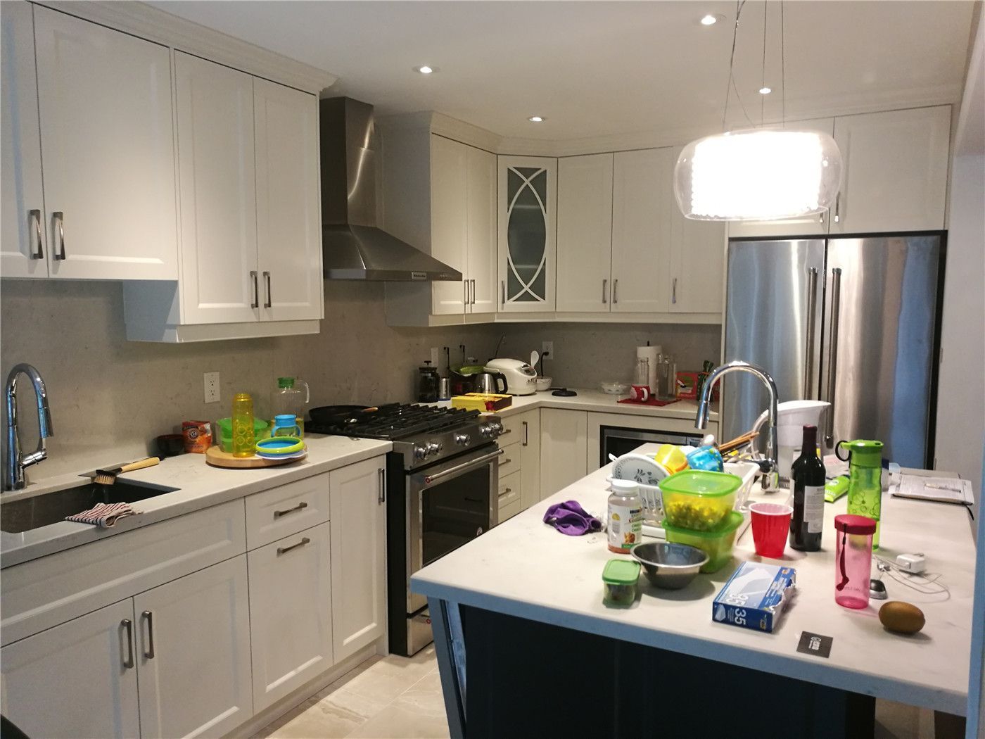 This Newmarket interior renovation showcases a modern kitchen remodel featuring custom white cabinetry, quartz countertops, a functional center island, and stainless steel appliances. Recessed lighting and a contemporary pendant light enhance brightness and usability, reflecting the quality craftsmanship of a trusted Toronto renovation company specializing in full kitchen upgrades.