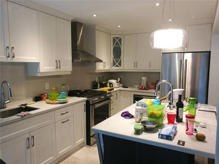 This Newmarket interior renovation showcases a modern kitchen remodel featuring custom white cabinetry, quartz countertops, a functional center island, and stainless steel appliances. Recessed lighting and a contemporary pendant light enhance brightness and usability, reflecting the quality craftsmanship of a trusted Toronto renovation company specializing in full kitchen upgrades.