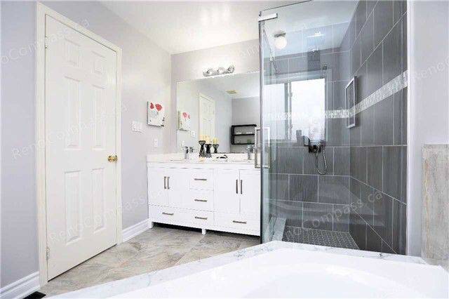 A beautifully remodeled bathroom featuring a frameless glass shower, sleek white vanity, and neutral tile design. Perfect inspiration for a modern home renovation in the Greater Toronto Area.