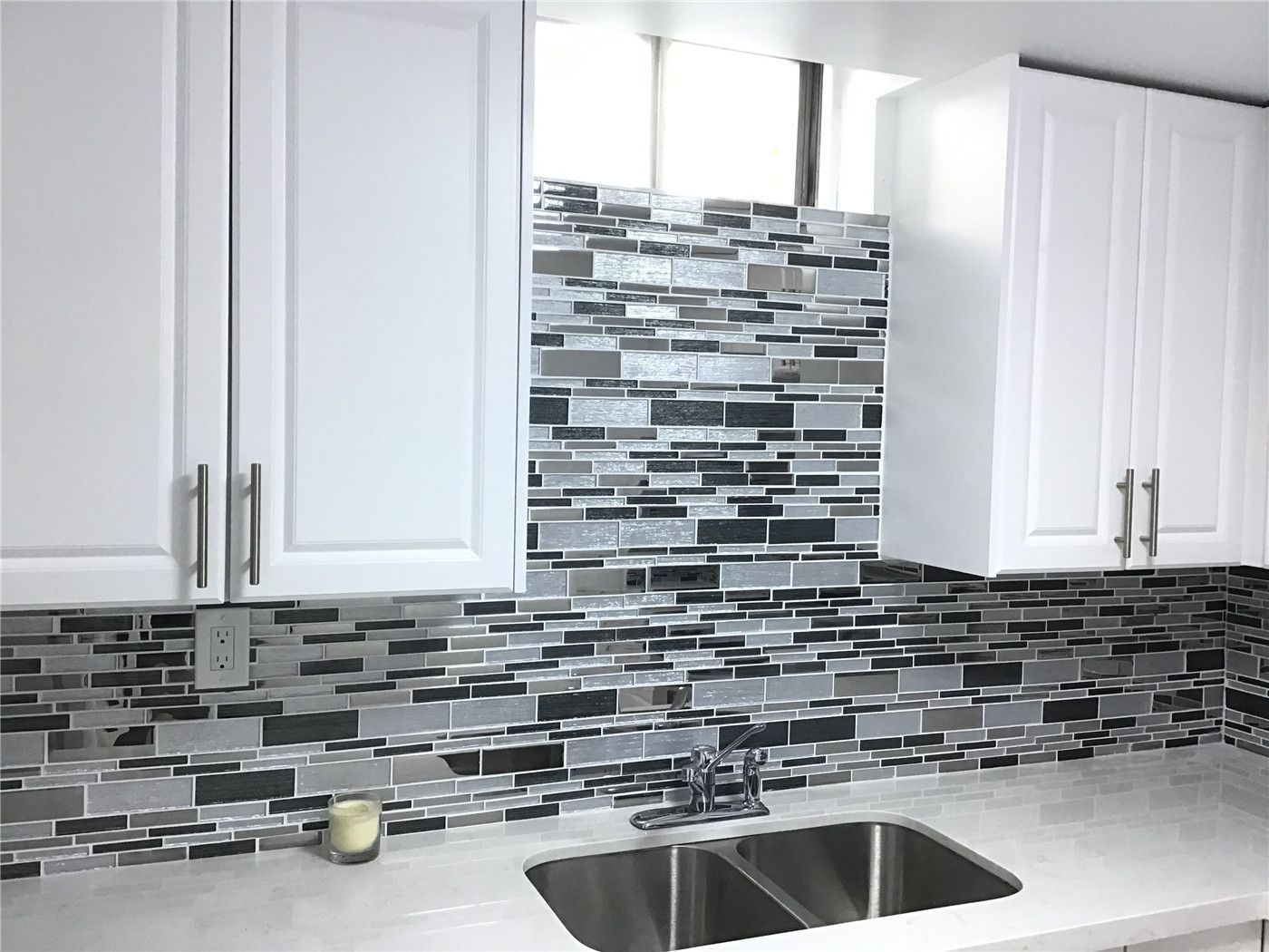 This Whitby basement renovation features a stylish L-shaped kitchen layout with crisp white shaker cabinets, stainless steel appliances, and a modern mosaic tile backsplash. The marble-look porcelain flooring enhances brightness and creates a clean, cohesive finish. Designed for functionality and efficiency, this basement kitchen is ideal for a secondary suite or rental-ready setup