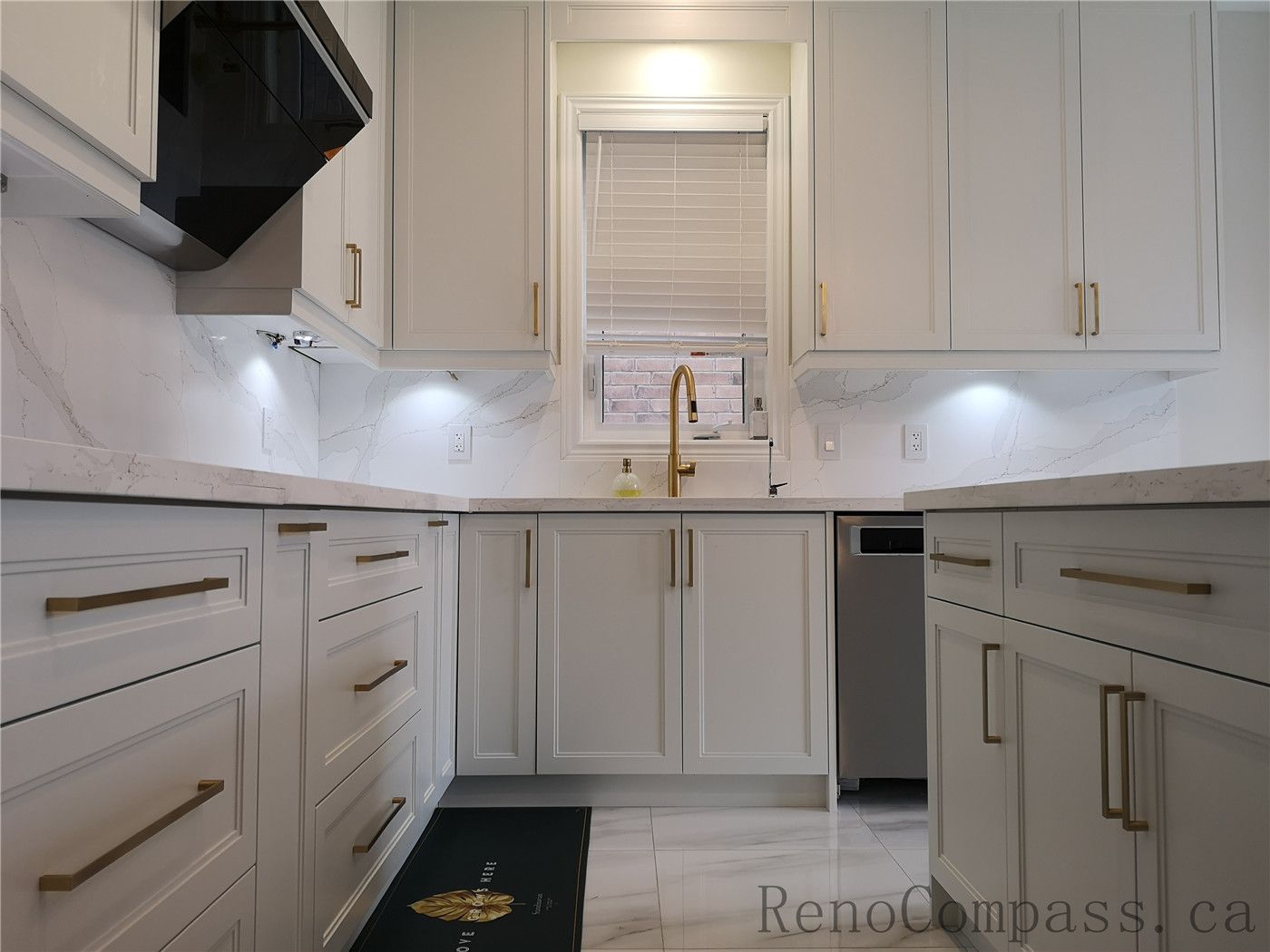 This Aurora kitchen renovation highlights custom island cabinetry with shaker-style doors, quartz countertops, and elegant brushed gold hardware. The modern layout integrates functional storage, under-cabinet lighting, and marble-style flooring to create a clean and sophisticated space. Completed by a professional Toronto renovation company focused on premium finishes, practical design, and high-quality craftsmanship.