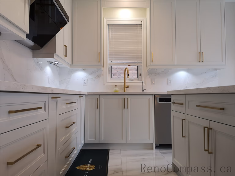 This Aurora kitchen renovation highlights custom island cabinetry with shaker-style doors, quartz countertops, and elegant brushed gold hardware. The modern layout integrates functional storage, under-cabinet lighting, and marble-style flooring to create a clean and sophisticated space. Completed by a professional Toronto renovation company focused on premium finishes, practical design, and high-quality craftsmanship.