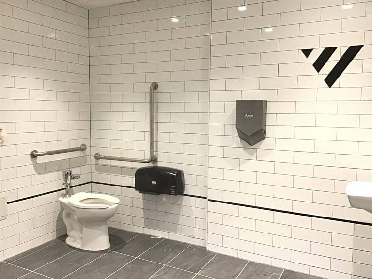 Accessible commercial washroom renovation in downtown Toronto featuring a barrier-free toilet, safety grab bars, and durable tile finishes, designed to meet accessibility standards and ensure comfort in high-traffic business environments.