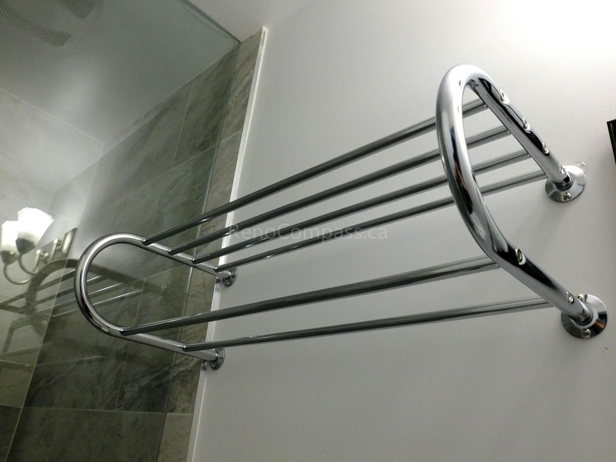 This image highlights a chrome wall-mounted towel rack installed as part of a North York interior renovation project. The accessory is securely fixed beside a frameless glass shower enclosure, offering practical towel storage while maintaining a clean and modern bathroom aesthetic. Paired with marble-look wall tiles and polished chrome finishes, the detail reflects thoughtful bathroom planning and quality installation by a professional Toronto renovation company.