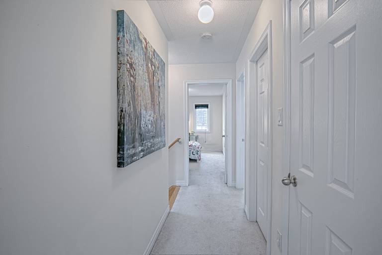 This modern hallway renovation features a clean neutral palette, soft carpeting, and bright overhead lighting that enhances the sense of openness throughout the upper floor. The streamlined layout connects bedrooms and living spaces seamlessly, while contemporary wall art adds visual interest and warmth. Designed to improve flow, comfort, and everyday functionality, this interior upgrade reflects the high-quality craftsmanship of a trusted Toronto renovation company specializing in full home renovation and modern residential interiors.