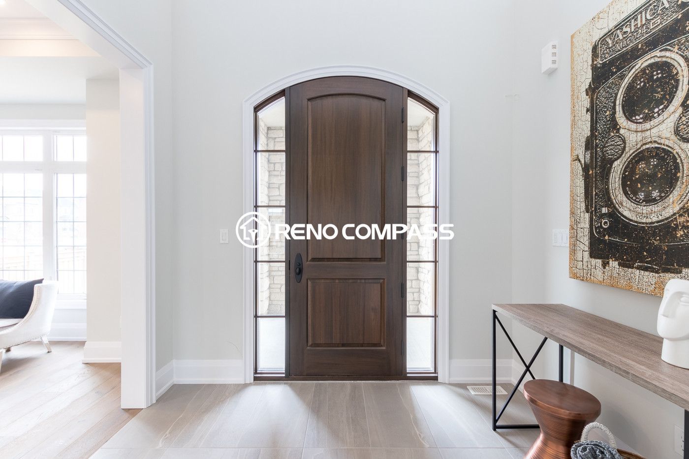 This image shows a bright and modern home entrance after a Newmarket flooring renovation project in Toronto. The homeowner selected engineered wood flooring, which provides the natural appearance and comfortable feel of solid hardwood while offering greater structural stability. Engineered wood floors are constructed with multiple layers of wood pressed together in a cross-grain structure, helping prevent expansion, cracking, and warping. This flooring upgrade enhances durability, improves moisture resistance, and creates a clean, elegant entry space for the home. Renovation completed by Reno Compass Inc., a Toronto renovation company specializing in flooring installation and interior upgrades.