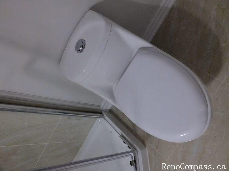 Efficient and stylish toilet installation as part of a Richmond Hill basement bathroom remodel, emphasizing clean lines and bright finishes by Reno Compass