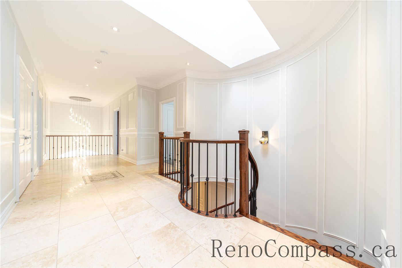 This Richmond Hill entire house interior renovation features a bright upper hallway and staircase area with custom iron railings, elegant wall paneling, and natural light from a large skylight. The refined layout and neutral finishes create a clean, spacious, and welcoming transition between floors. Completed by a professional Toronto renovation company, this staircase and hallway renovation highlights quality craftsmanship, safety, and timeless interior design.