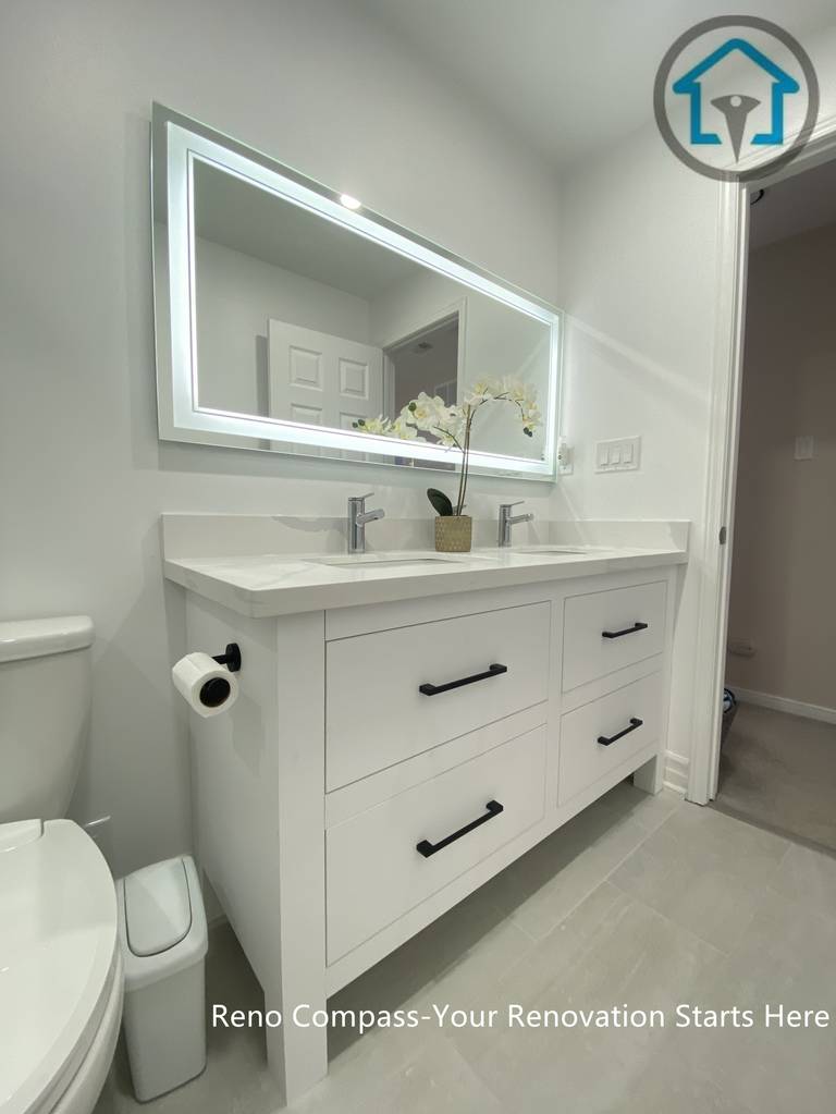 This Pickering bathroom renovation features a custom double vanity designed for both storage efficiency and everyday comfort. Clean-lined white cabinetry is paired with matte black handles for subtle contrast, while the integrated LED mirror provides even lighting and visual depth. The layout keeps the space organized and functional without compromising on a clean, modern aesthetic.