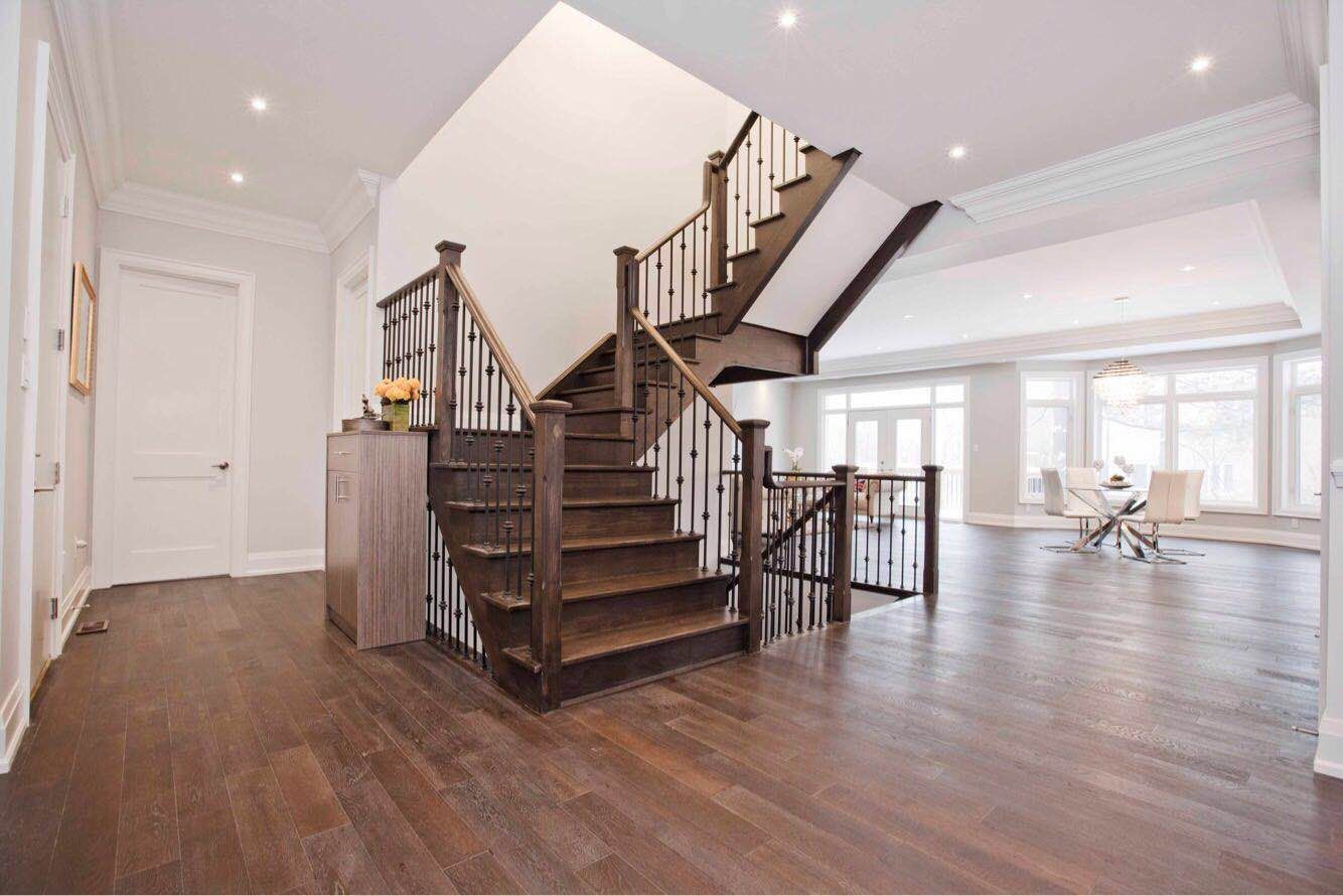 Custom hardwood staircase completed as part of a Toronto design build custom build project, featuring elegant railings, wide plank hardwood flooring, and an open-concept layout connecting the main living areas. This whole house renovation Toronto project highlights detailed craftsmanship and architectural design, creating a striking focal point that enhances the flow and luxury feel of the custom home interior.