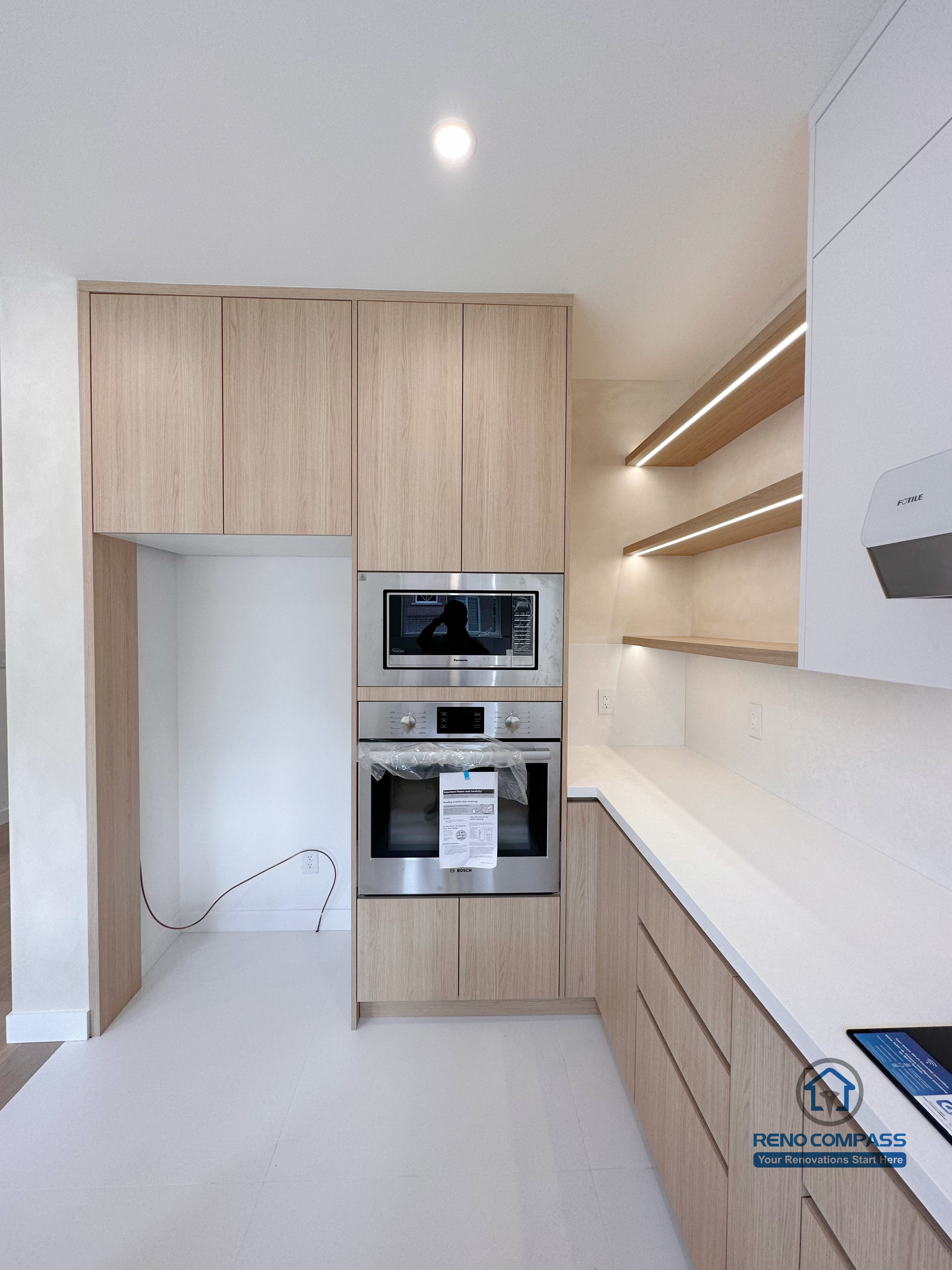 This Markham kitchen renovation showcases built-in appliances, full-height wood cabinetry, and open shelving with integrated lighting. The design maximizes storage efficiency while maintaining a clean, modern aesthetic suited for everyday cooking and long-term use.