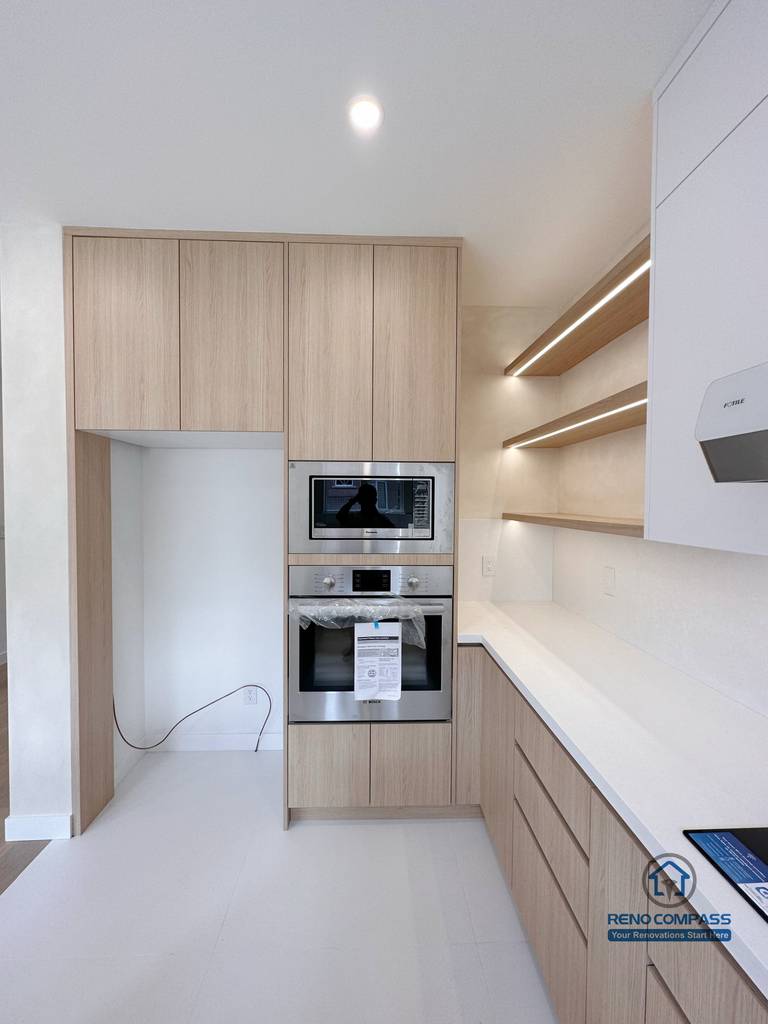 This Markham kitchen renovation showcases built-in appliances, full-height wood cabinetry, and open shelving with integrated lighting. The design maximizes storage efficiency while maintaining a clean, modern aesthetic suited for everyday cooking and long-term use.