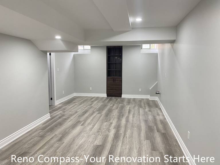 This finished basement in Aurora features a versatile open space designed for multiple uses, including a family lounge, home gym, or media room. The renovation focuses on maximizing headroom through clean ceiling transitions, combined with recessed lighting to evenly brighten the space. Neutral wall colors and durable wood-look flooring create a calm, modern atmosphere while maintaining practicality for everyday use. Thoughtful layout planning ensures smooth circulation and future flexibility. Completed by Reno Compass, a Toronto renovation contractor specializing in basement renovations.