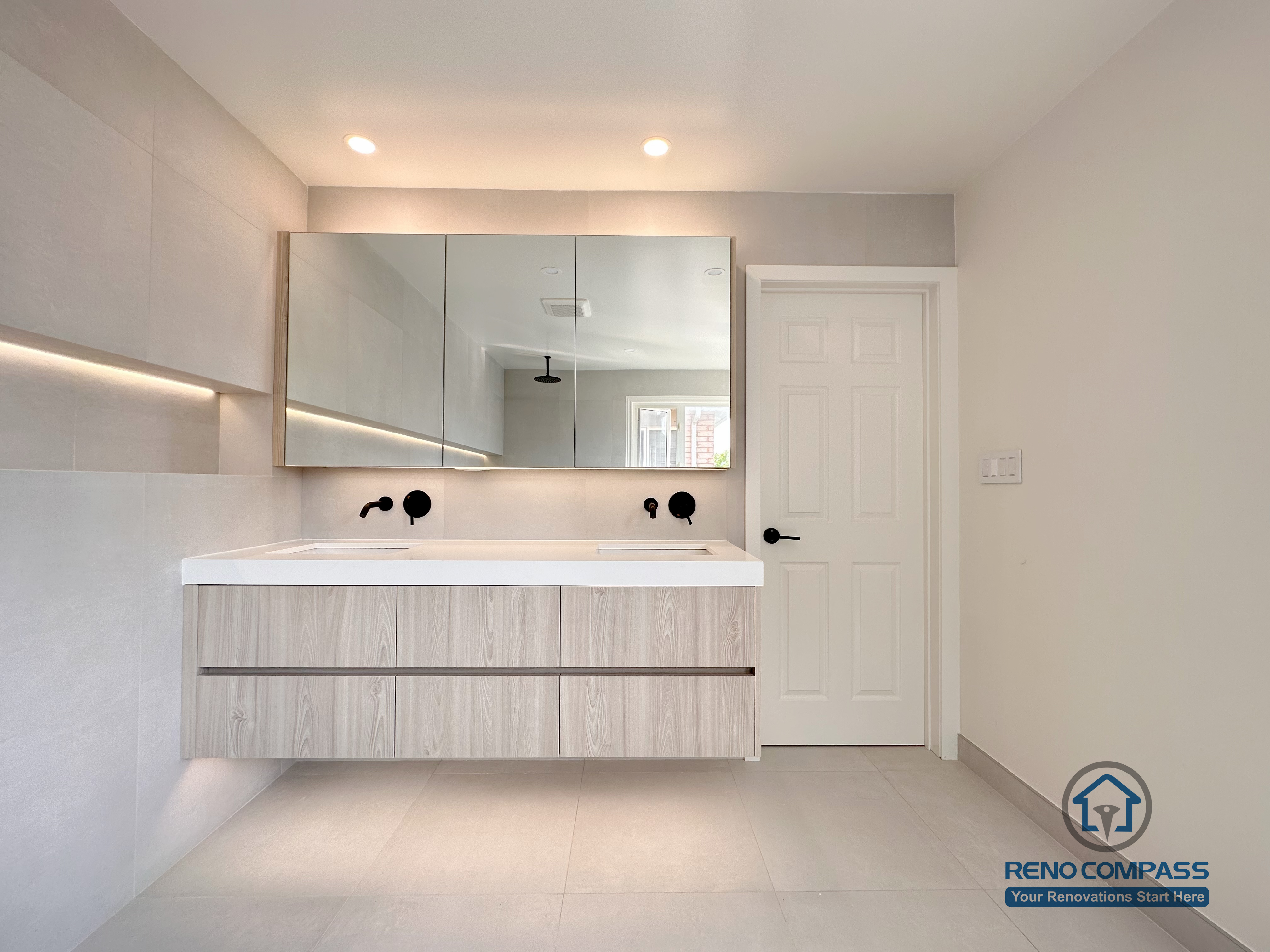 Modern bathroom renovation in Markham showcasing a floating double vanity, integrated mirror cabinets, and soft ambient lighting. The clean-lined design, neutral finishes, and wall-mounted fixtures create a spacious, contemporary bathroom with enhanced functionality and visual balance.