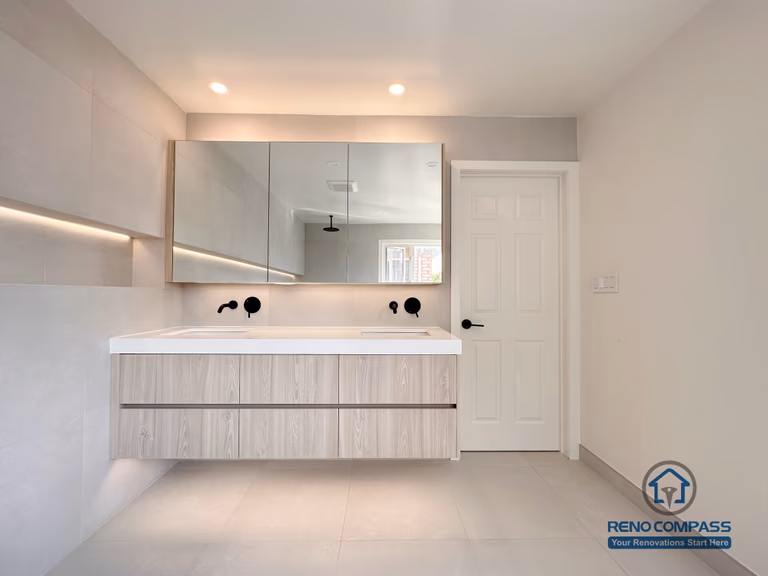 Modern bathroom renovation in Markham showcasing a floating double vanity, integrated mirror cabinets, and soft ambient lighting. The clean-lined design, neutral finishes, and wall-mounted fixtures create a spacious, contemporary bathroom with enhanced functionality and visual balance.